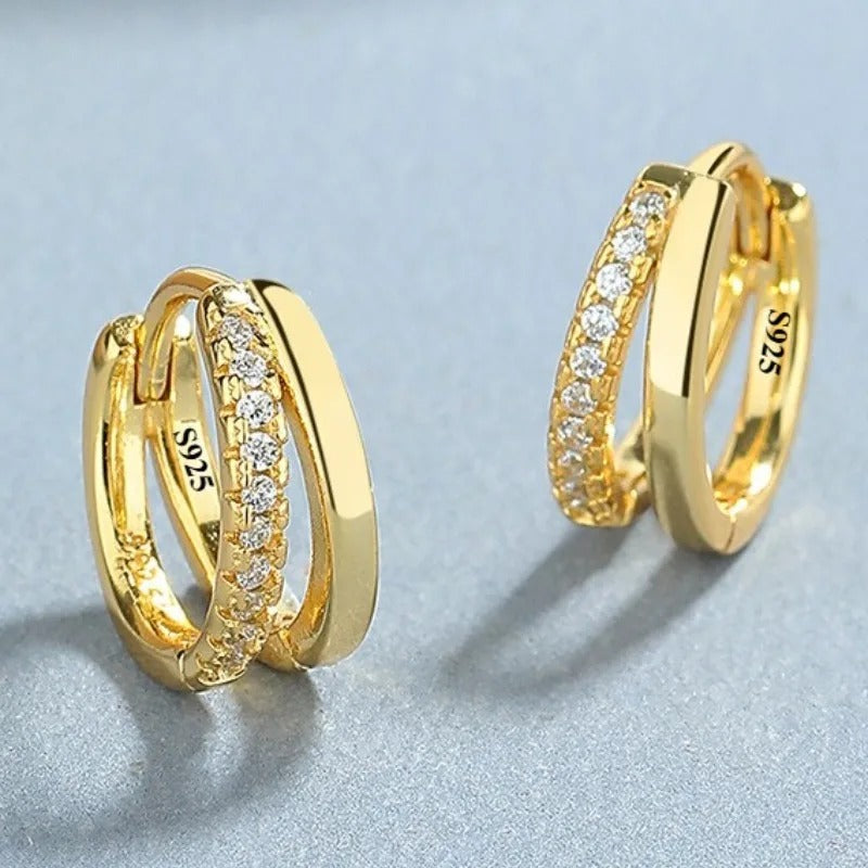 Gold hoop earrings with diamond accents on a light gray background