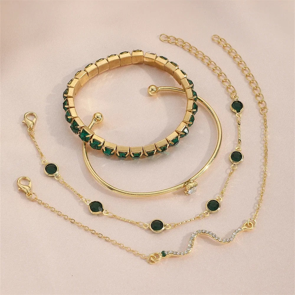 Gold jewelry set with green gemstones on a beige background