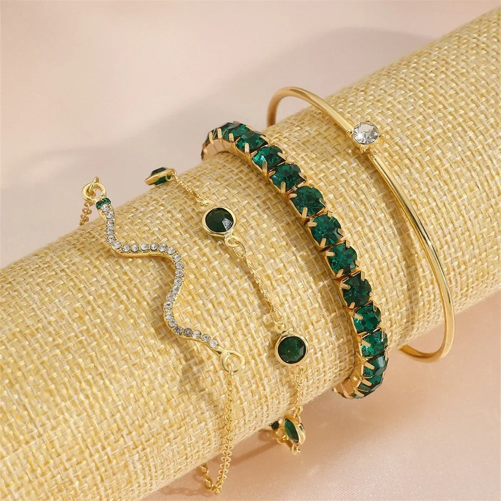 Set of gold and green gemstone jewelry on a beige textured surface