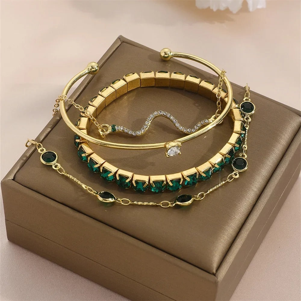 Set of gold bracelets with green gemstones on a brown jewelry box