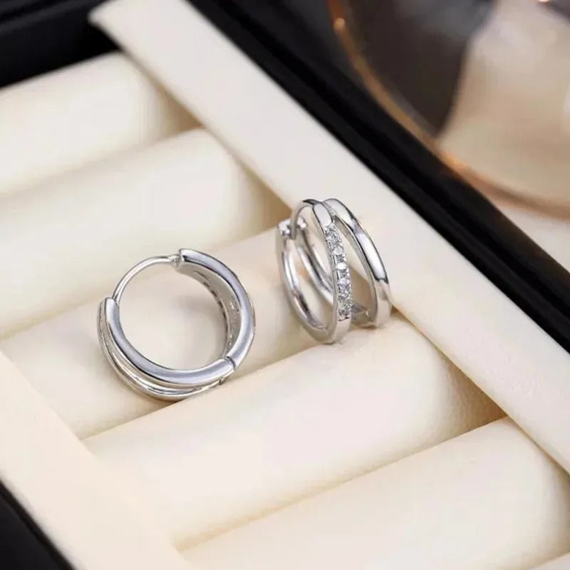 Silver hoop earrings on a soft beige surface
